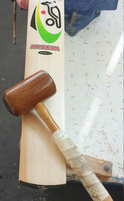 Knocking in a new bat with a mallet in the Cricket Express workshop